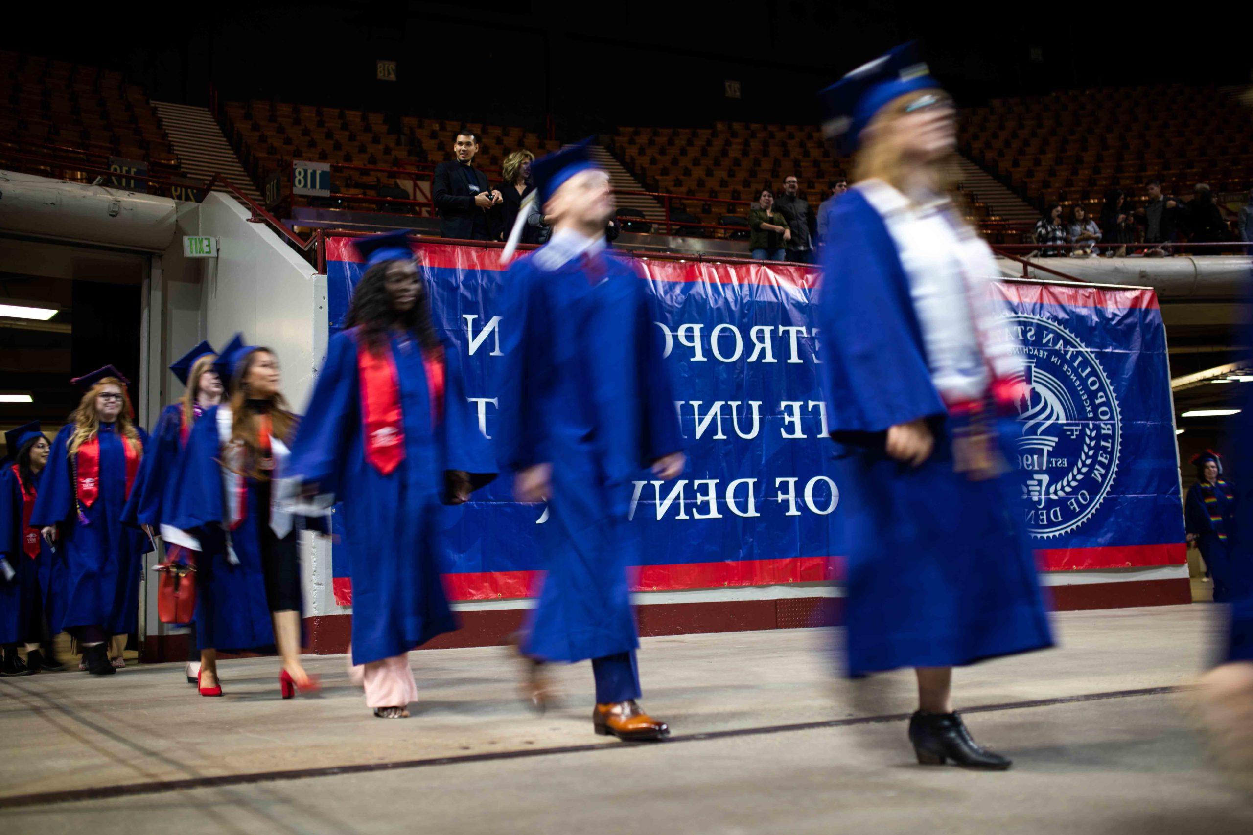 Graduates walking quickly into the Denver Coliseum.