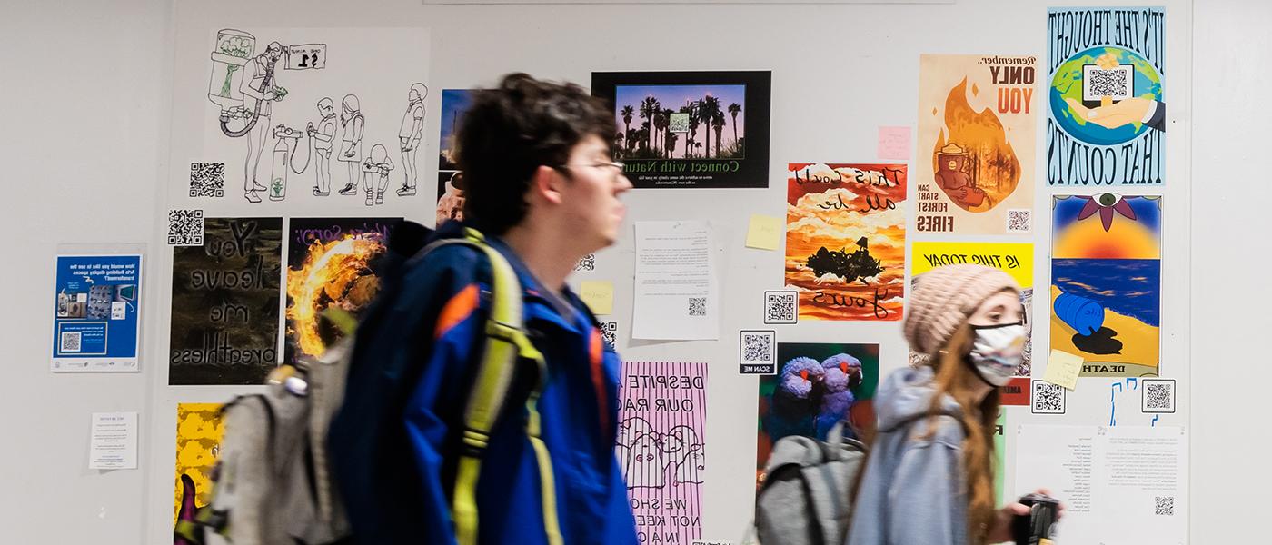 Students between classes walk through the hallways and pass by artworks posted on the bulletin boards.